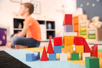 Photo of Castle made from cubes and little boy with autistic disorder on background