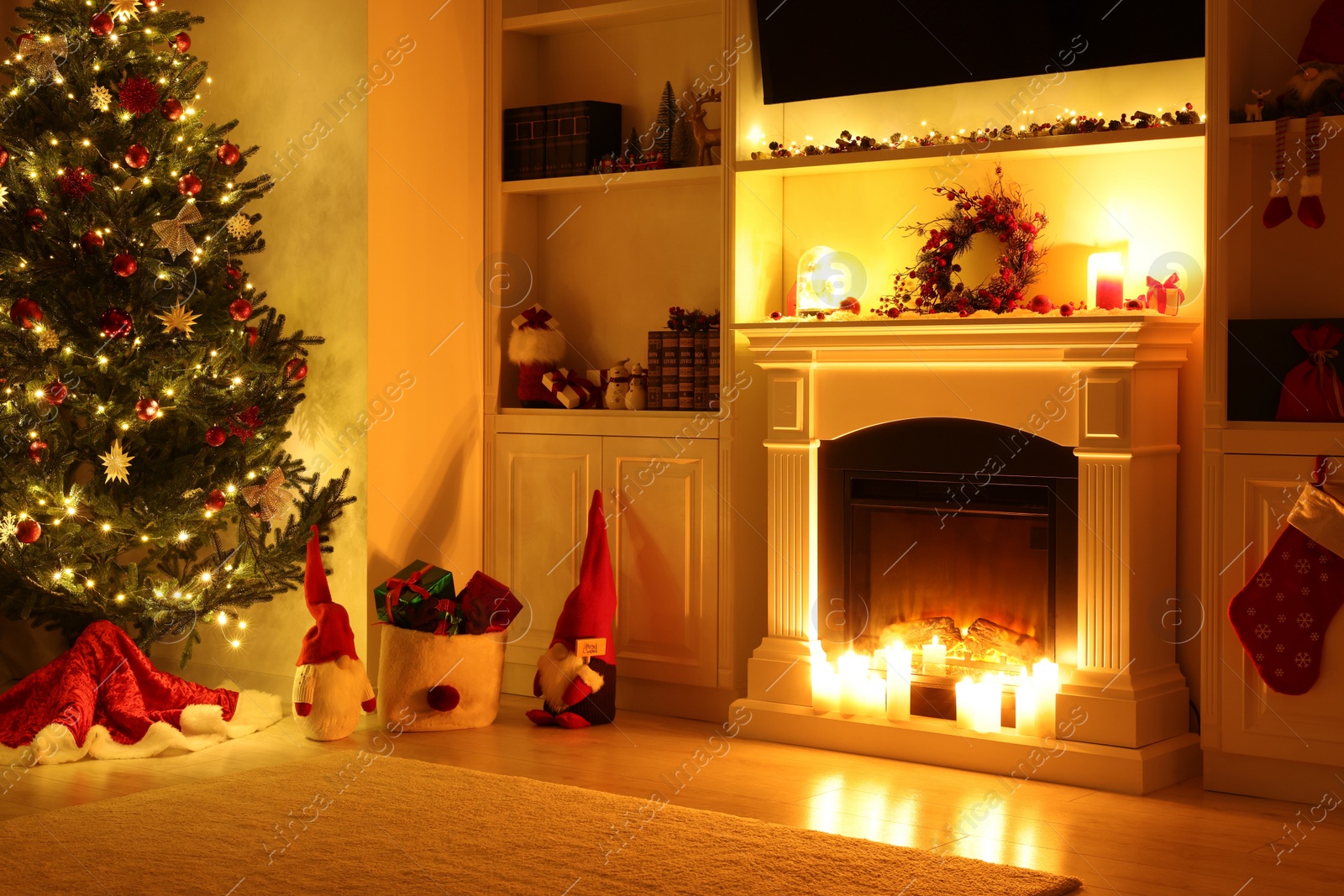 Photo of Cosy room with fireplace and burning candles in evening. Christmas atmosphere