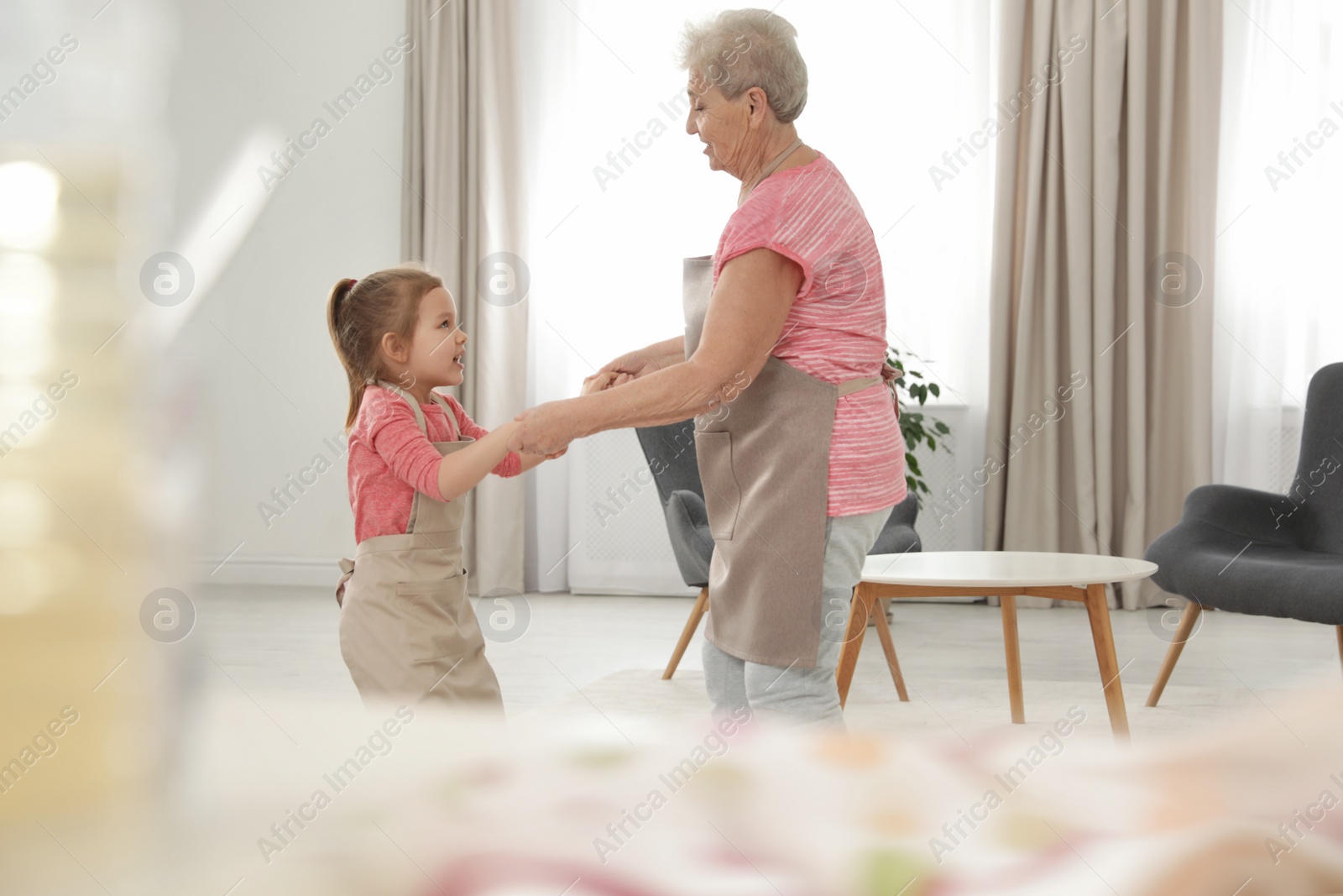 Photo of Cute girl and her grandmother dancing at home