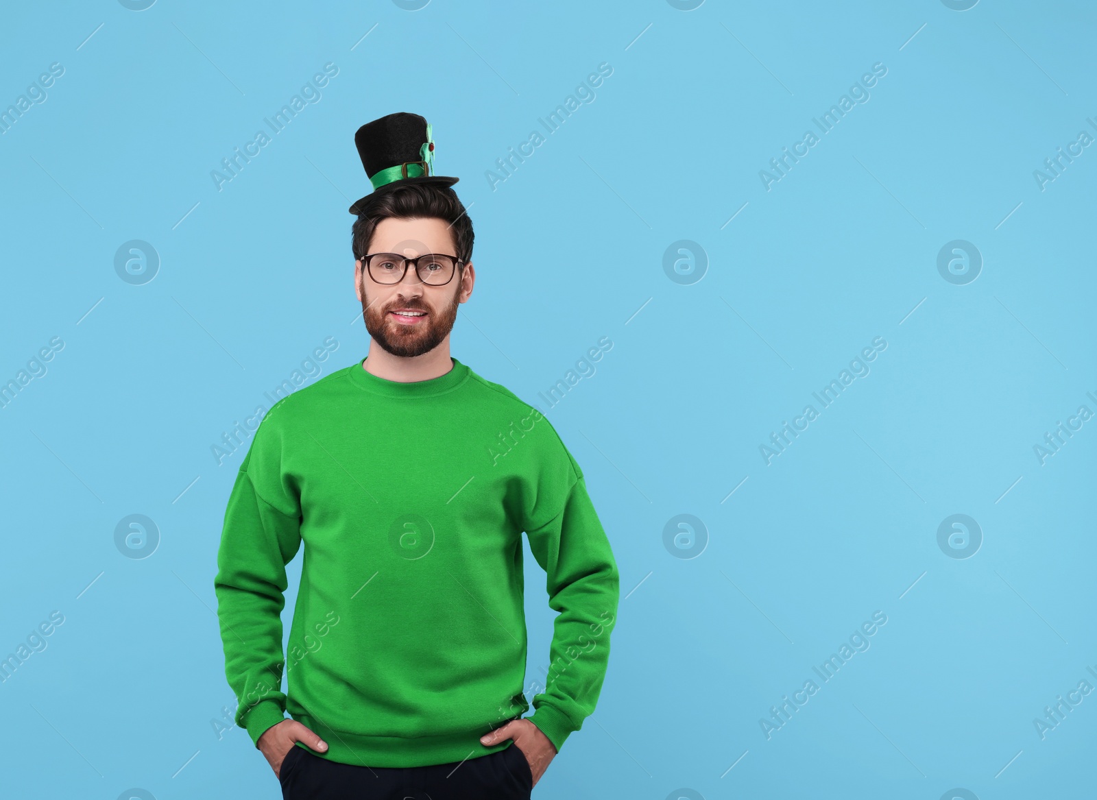 Image of St. Patrick's day party. Man in leprechaun hat on light blue background. Space for text