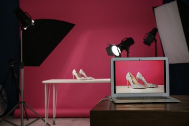 Photo of Shooting of women's shoes for product promotion in photo studio, focus on laptop