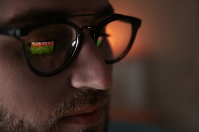 Photo of Young man wearing glasses on blurred background, closeup. Ophthalmology service