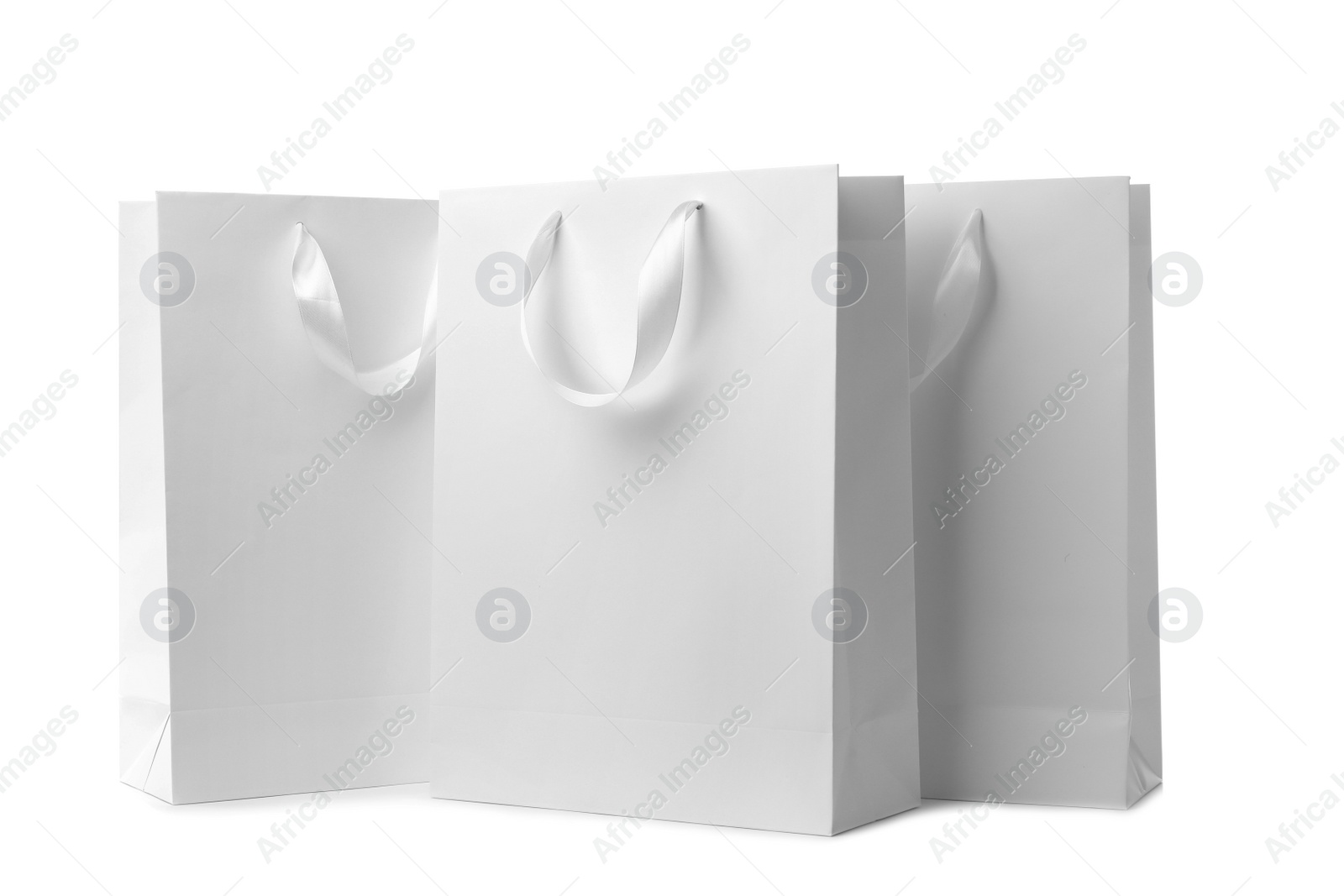 Photo of Paper shopping bags with ribbon handles on white background. Mockup for design