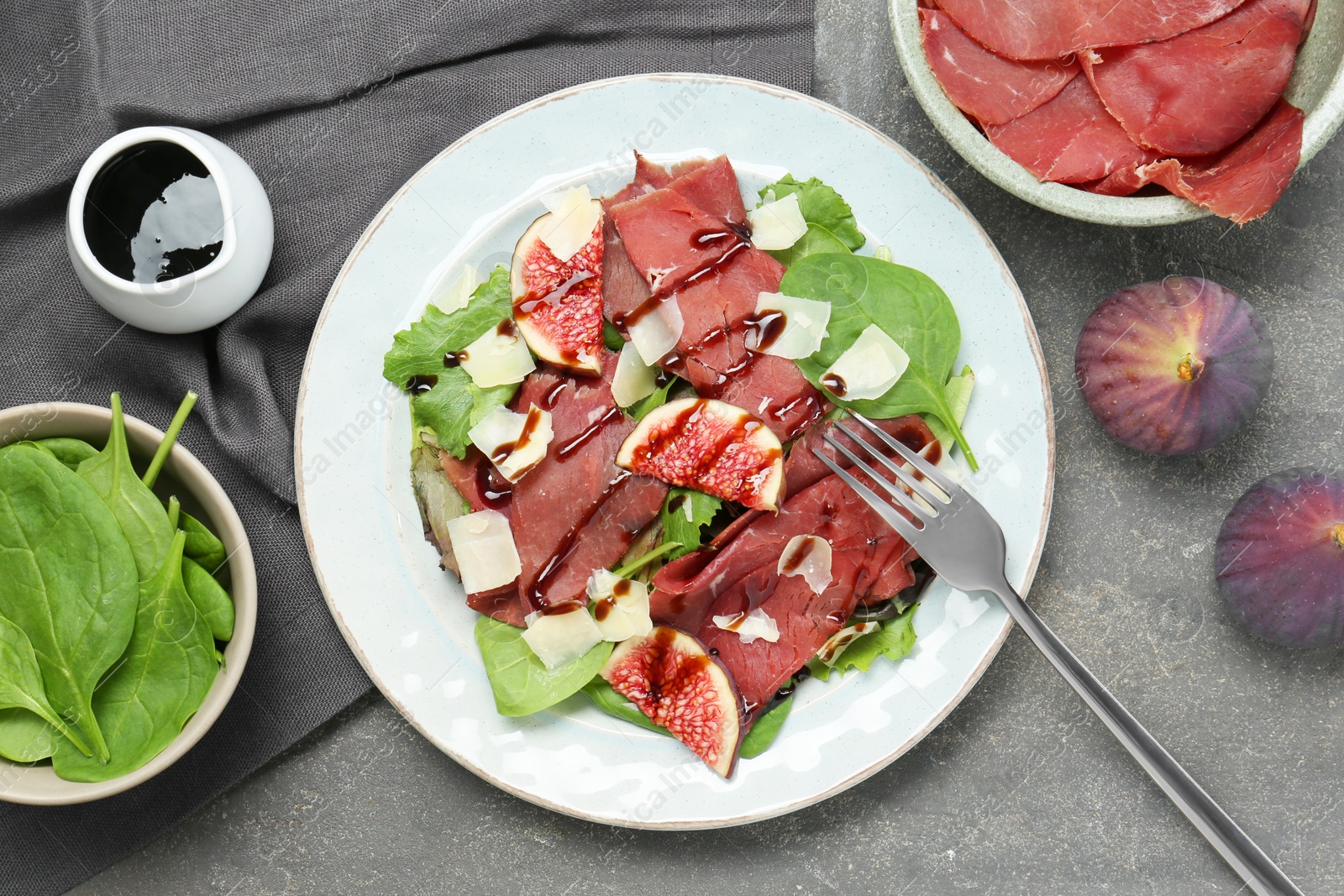 Photo of Flat lay composition with delicious bresaola salad on grey textured table