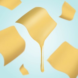 Image of Slices of cheese falling on light blue background