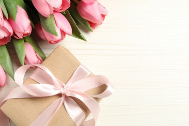 Happy Mother's Day. Beautiful pink tulips and gift box on white wooden table, flat lay. Space for text