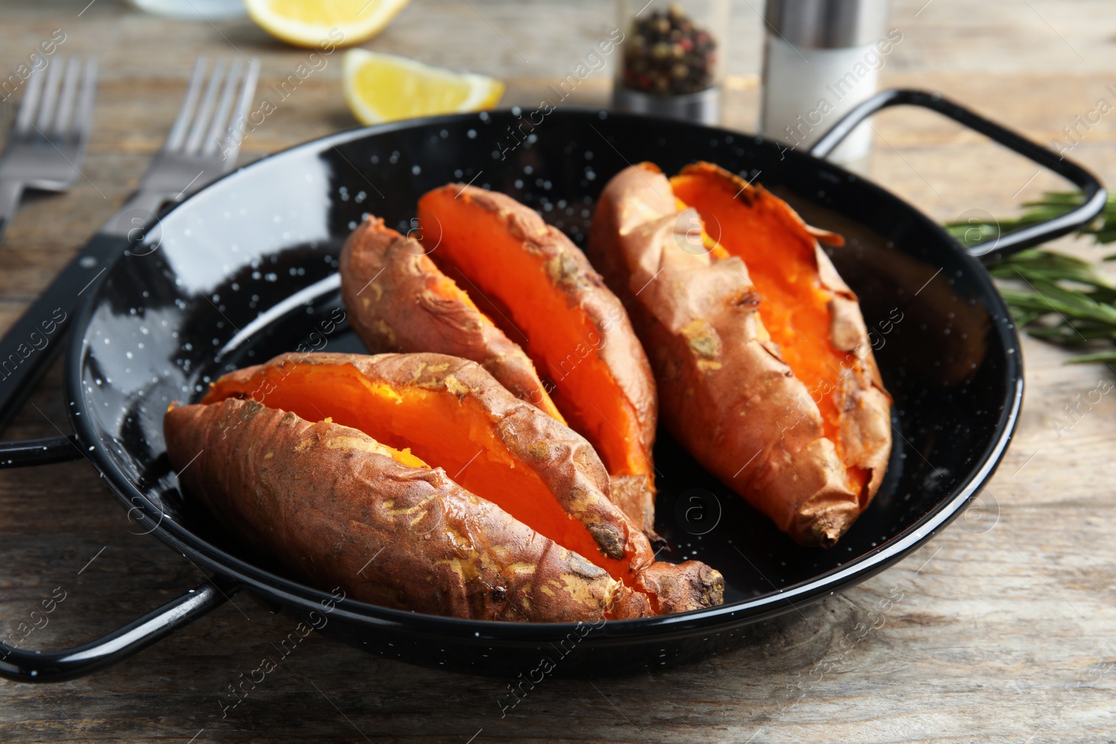 Photo of Dish with baked sweet potatoes on wooden table, closeup