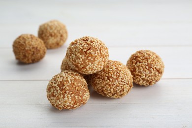 Photo of Delicious sesame balls on white wooden table, closeup
