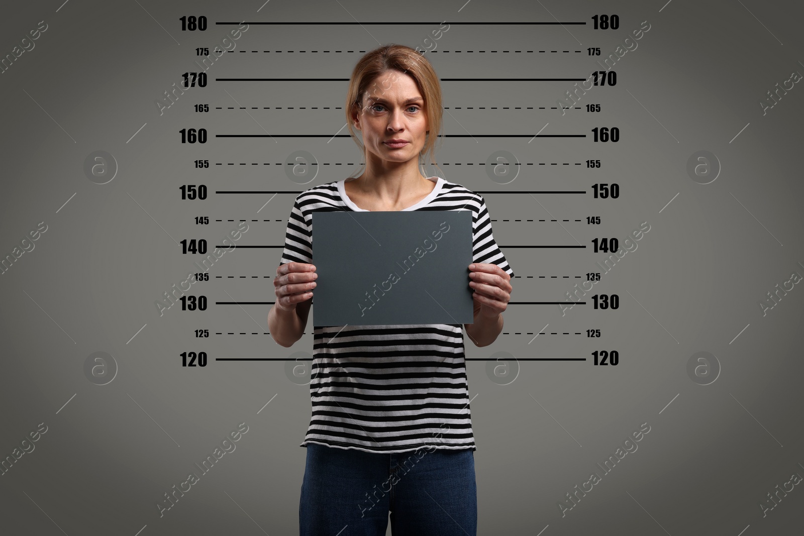 Image of Criminal mugshot. Arrested woman with blank card against height chart