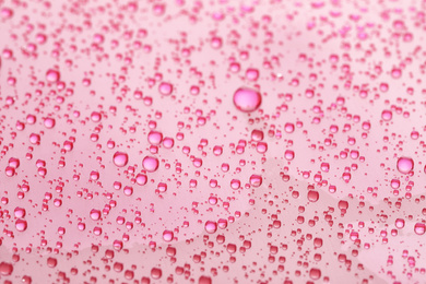 Photo of Water drops on pink background, closeup view