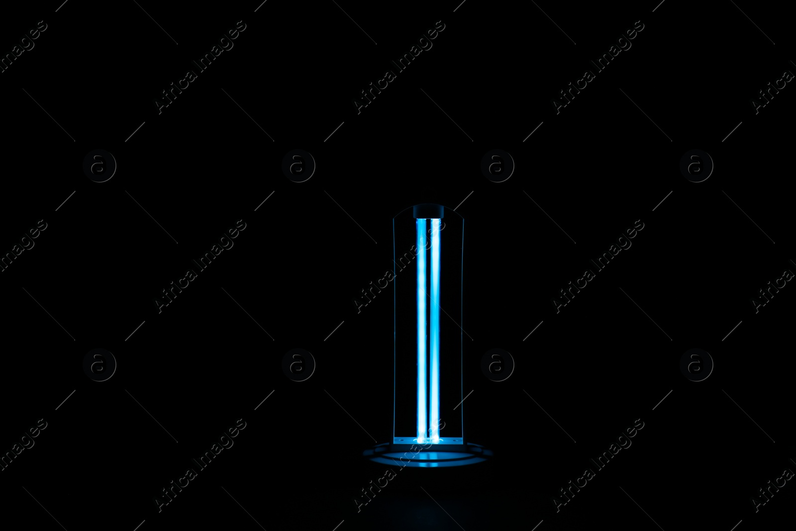 Photo of Modern ultraviolet lamp glowing on black background