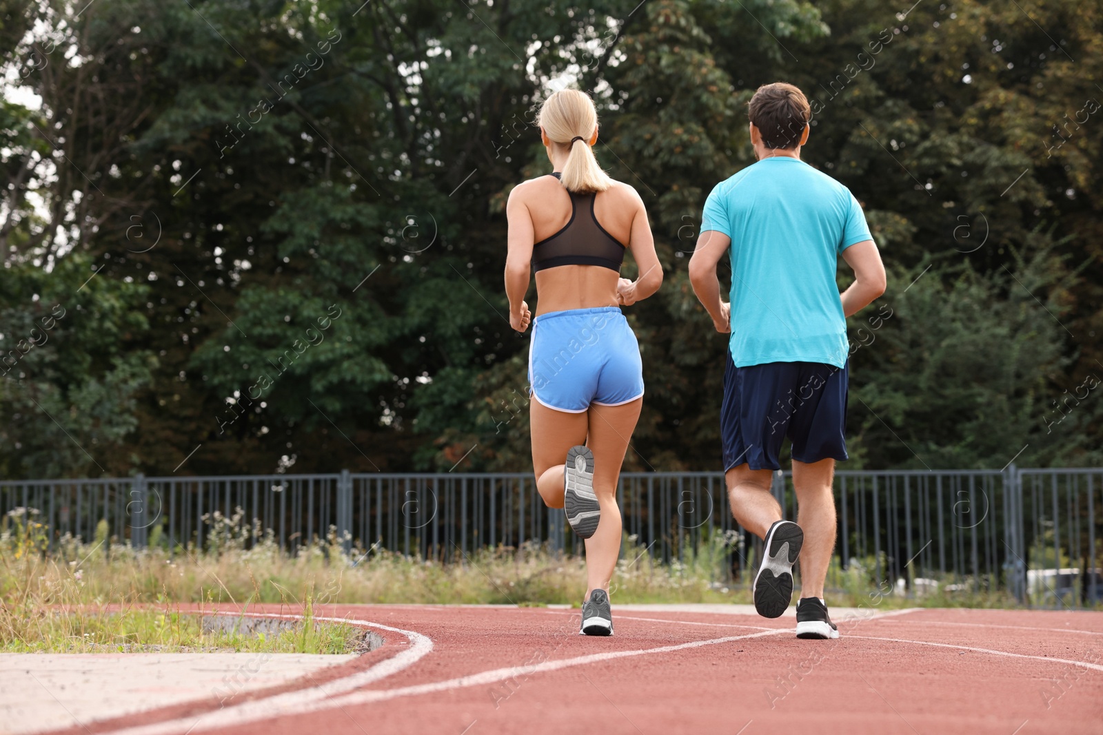 Photo of Healthy lifestyle. Sporty couple running at stadium, back view