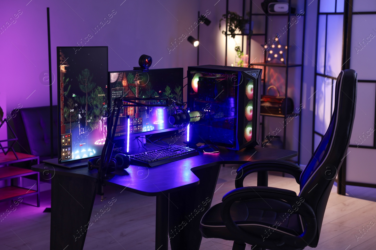 Photo of Playing video games. Stylish room interior with modern computer and gaming chair in neon lights