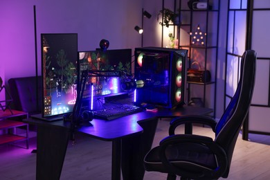 Playing video games. Stylish room interior with modern computer and gaming chair in neon lights