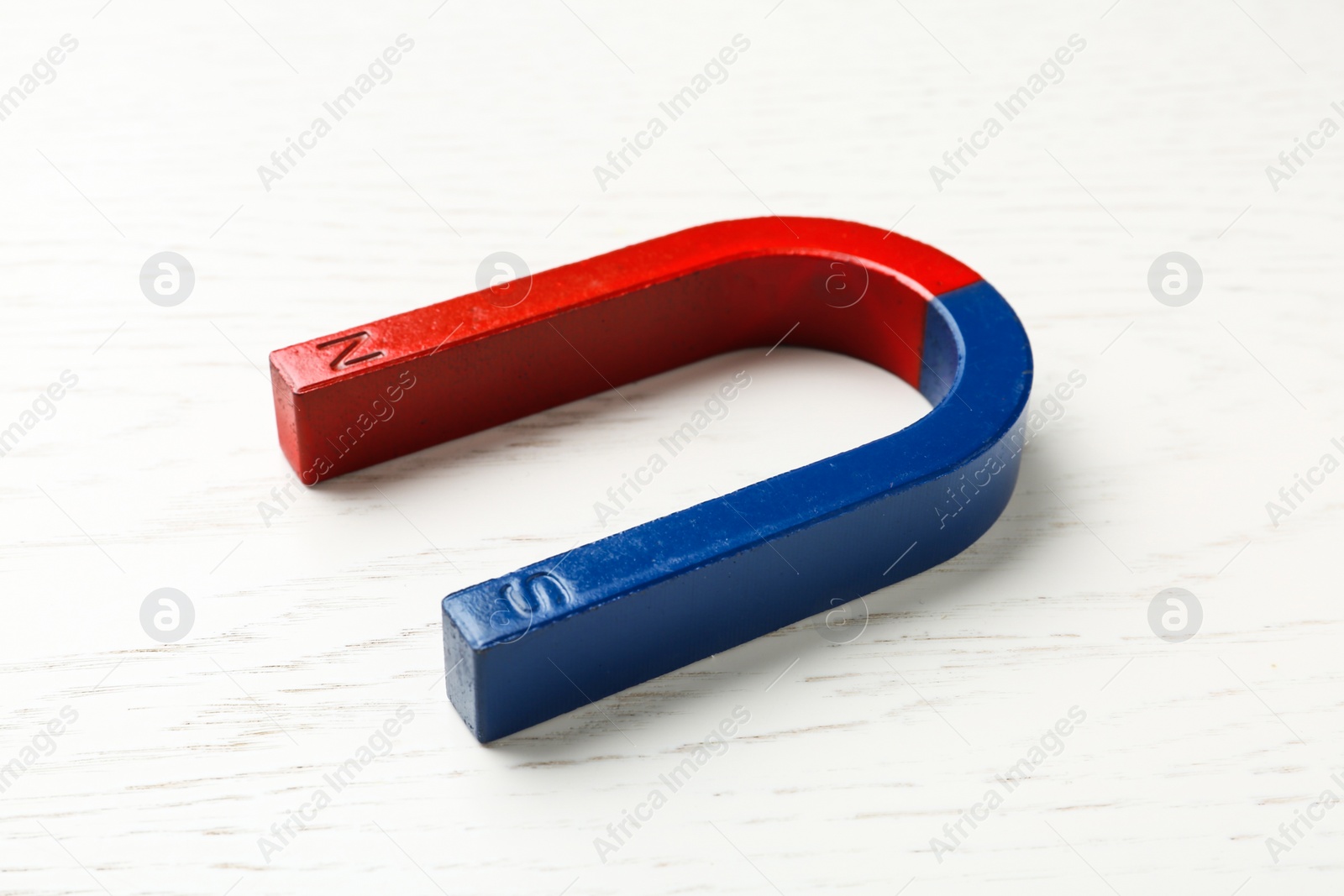 Photo of Red and blue horseshoe magnet on wooden background