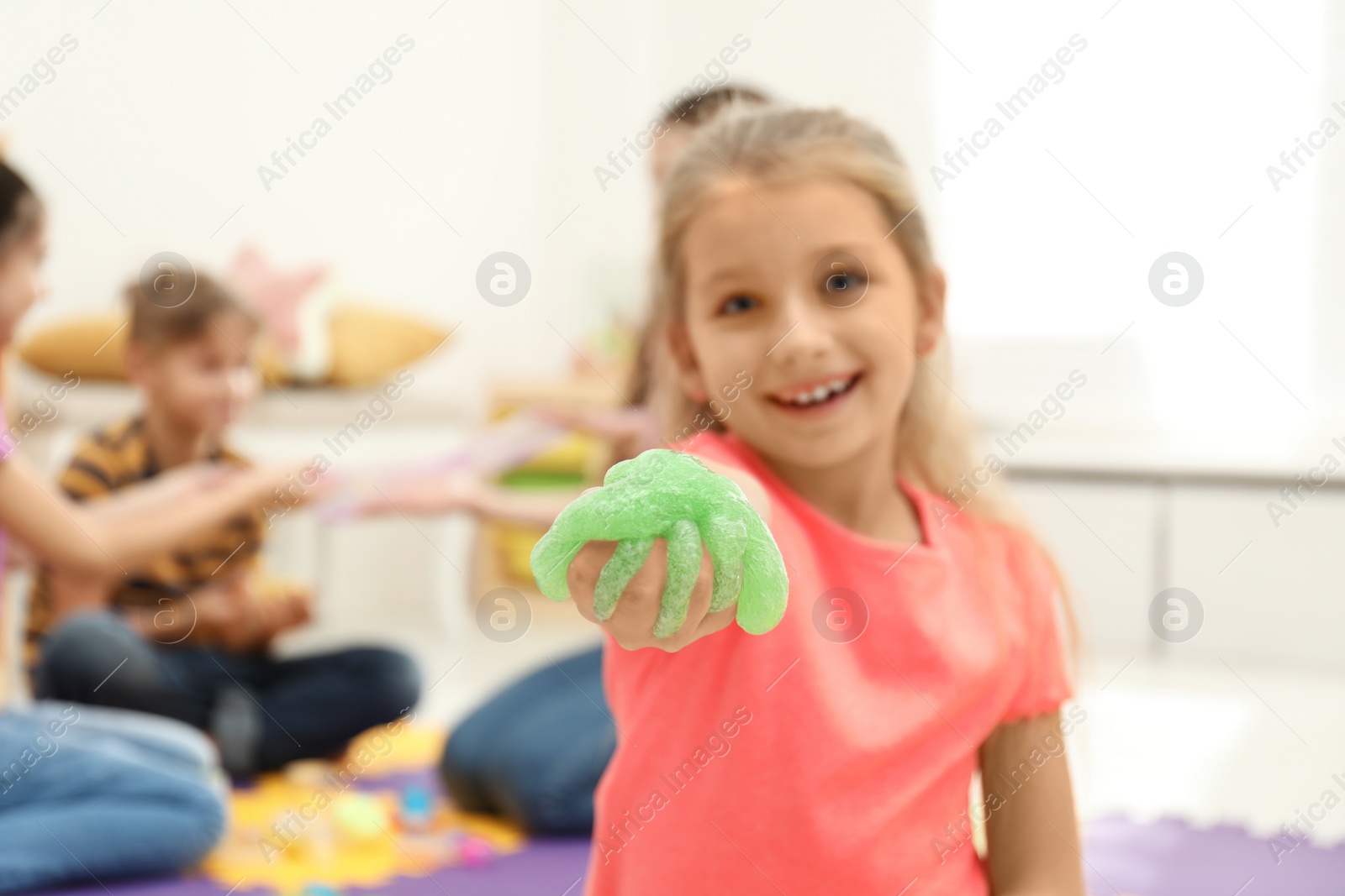 Photo of Little girl with slime in playroom, focus on hand