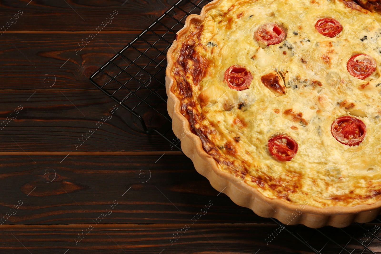 Photo of Delicious quiche with cheese and tomatoes on wooden table, closeup. Space for text