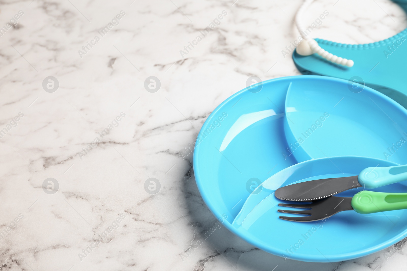 Photo of Section plate with fork and knife on white marble table, space for text. Serving baby food