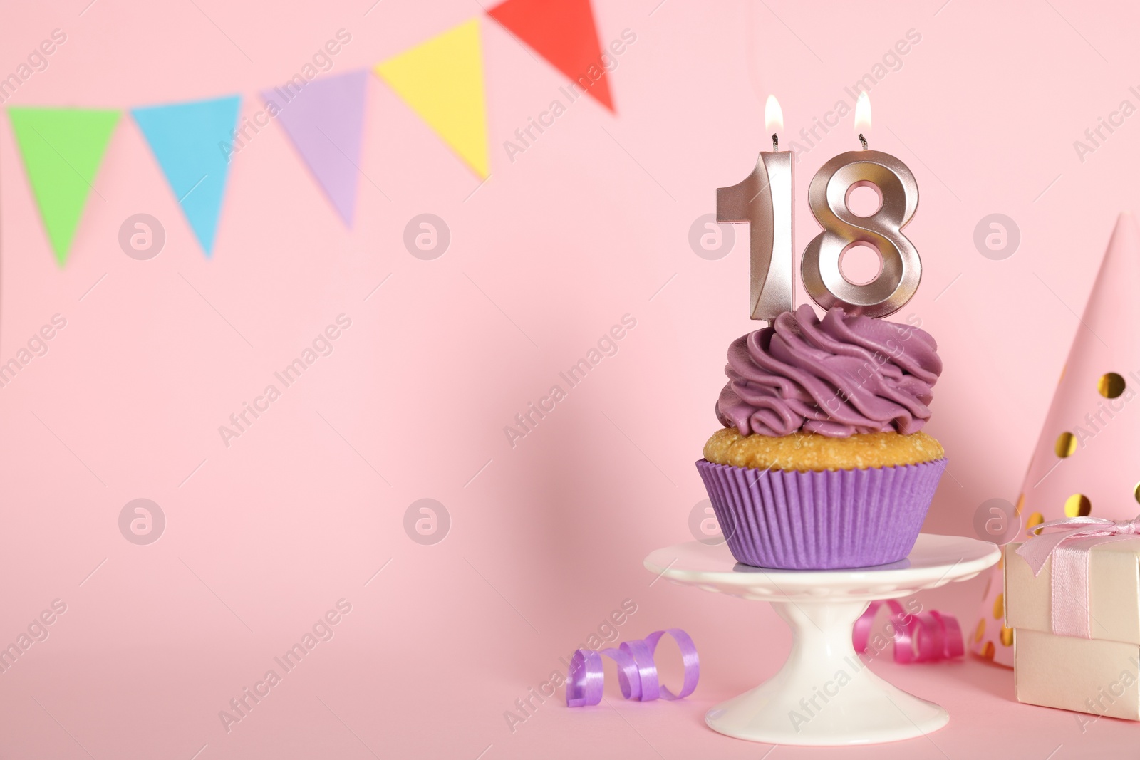 Photo of Delicious cupcake with number shaped candles on pink background, space for text. Coming of age party - 18th birthday