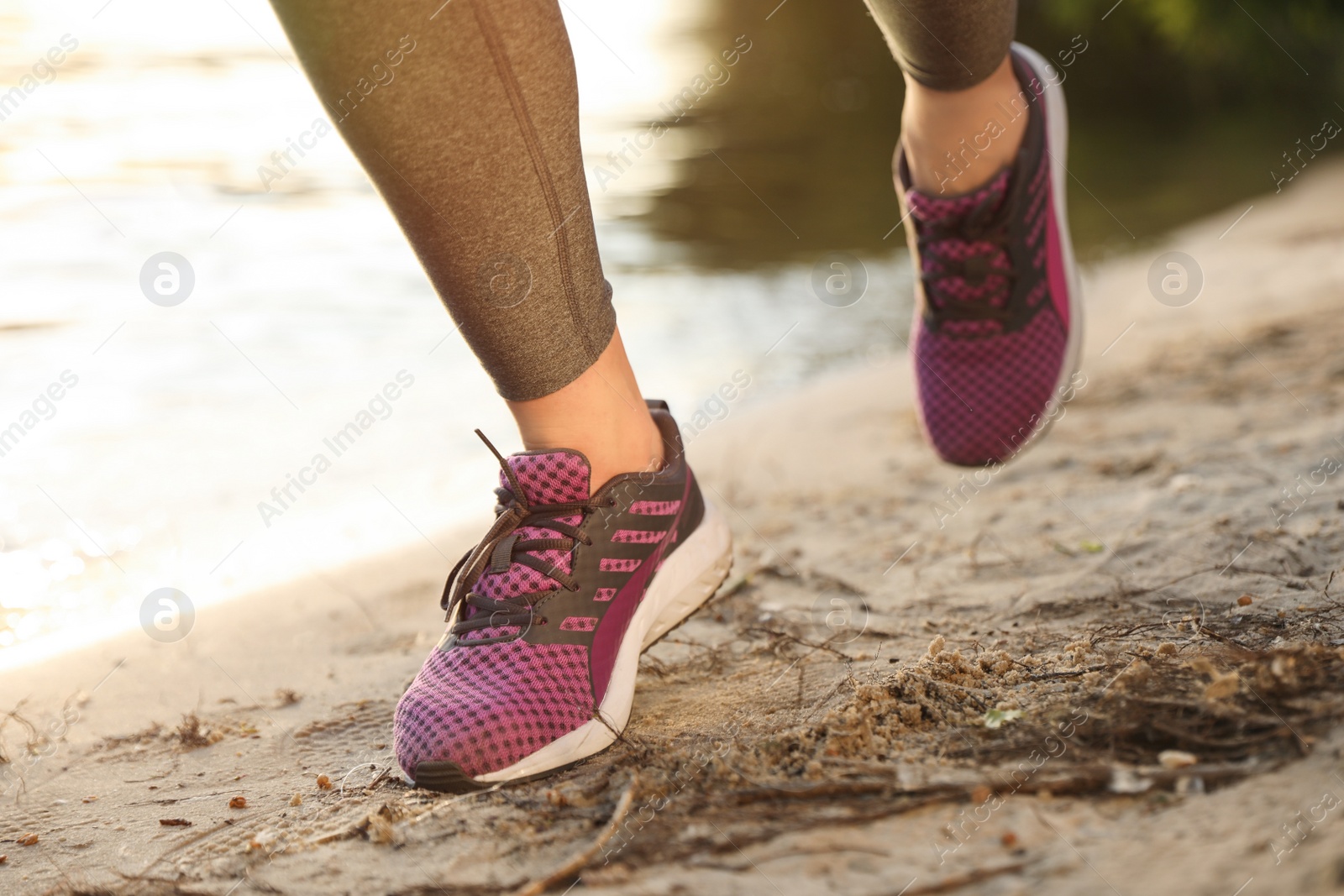 Photo of Young woman running near river on sunny day, closeup