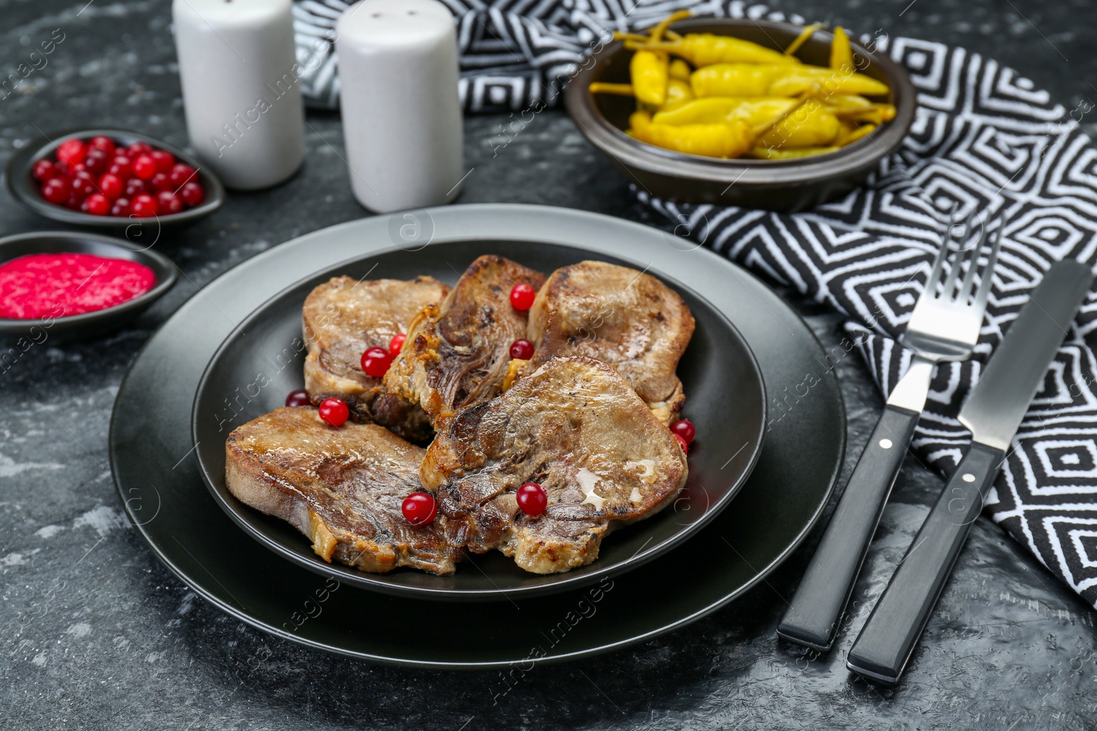 Photo of Tasty beef tongue pieces served on dark table