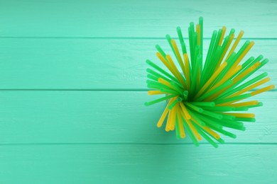 Colorful plastic drinking straws on turquoise wooden table, top view. Space for text