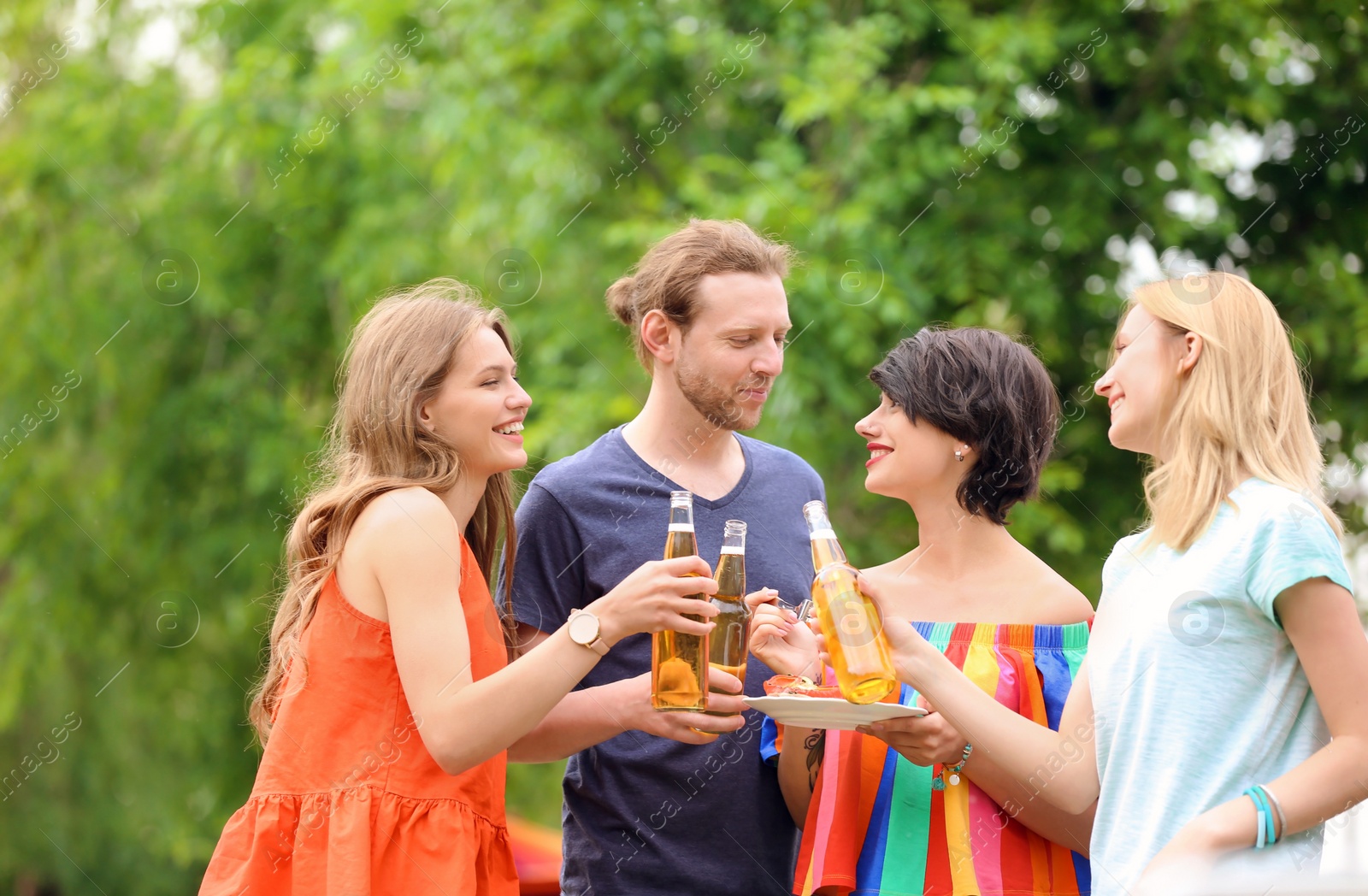 Photo of Young people with bottles of beer and food outdoors. Summer barbecue