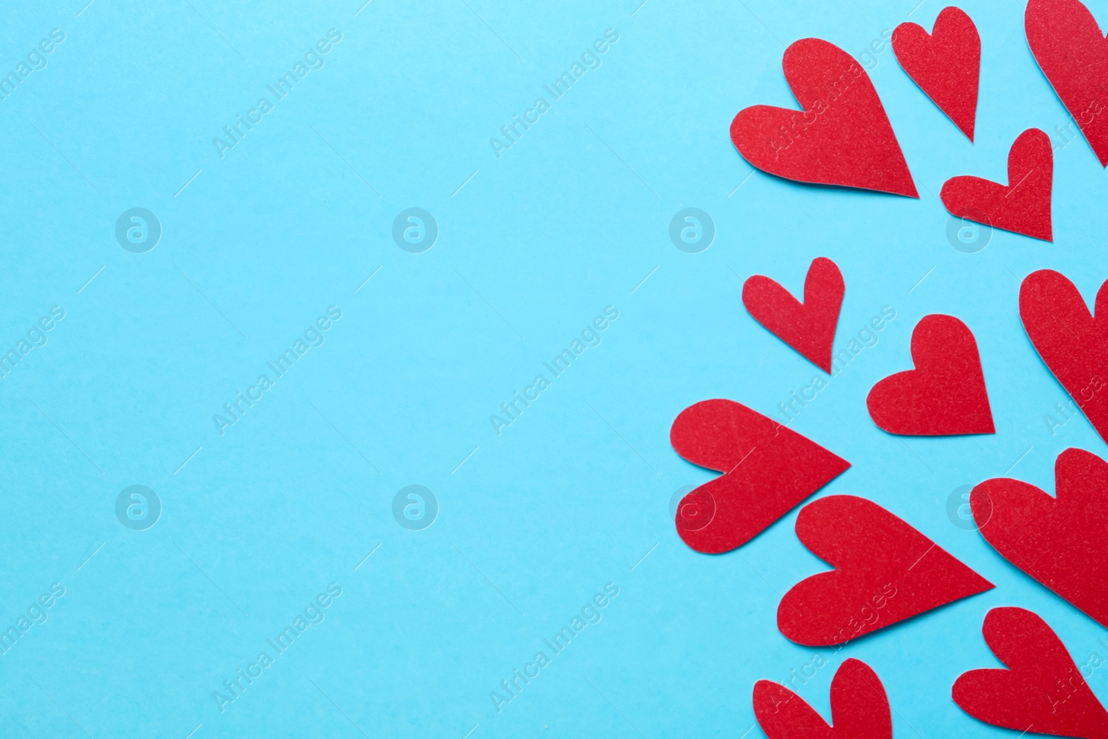 Photo of Red decorative hearts and space for text on light blue background, flat lay. Valentine's Day