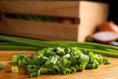 Chopped green spring onion on wooden board, closeup