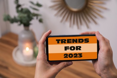 Image of Trends For 2023 text on phone display. Man using gadget at home, closeup