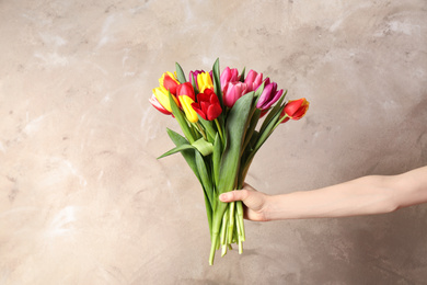 Photo of Woman holding beautiful spring tulips on light background, closeup