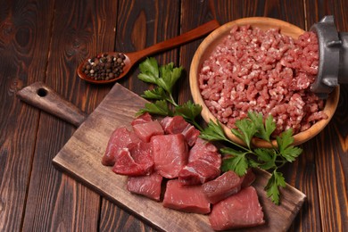 Photo of Manual meat grinder with beef, peppercorns and parsley on wooden table