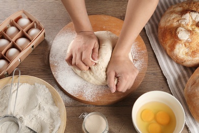 Photo of Female baker preparing bread dough at kitchen table, above view
