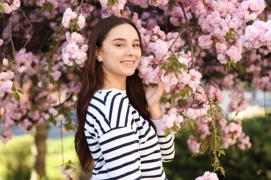 Beautiful woman near blossoming tree on spring day