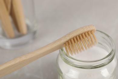Bamboo toothbrush and jar of baking soda on table, closeup
