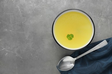Photo of Delicious chicken bouillon with parsley on grey table, top view. Space for text