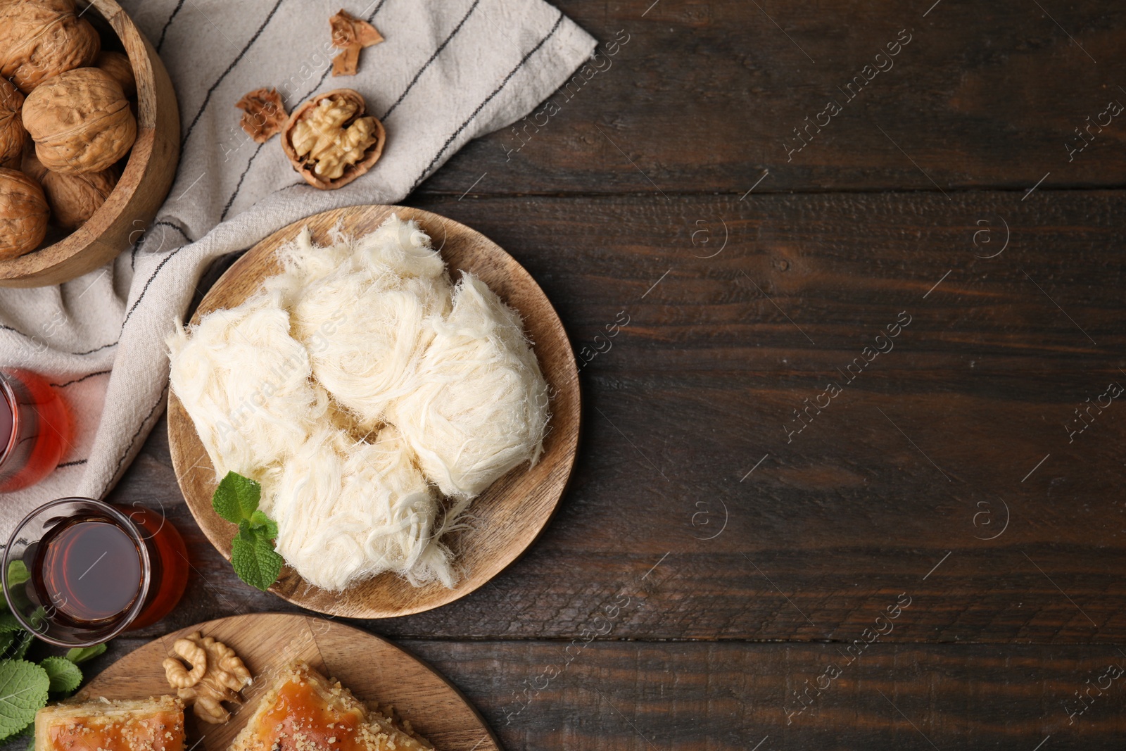 Photo of Eastern sweets. Tasty Iranian pashmak and tea on wooden table, flat lay. Space for text