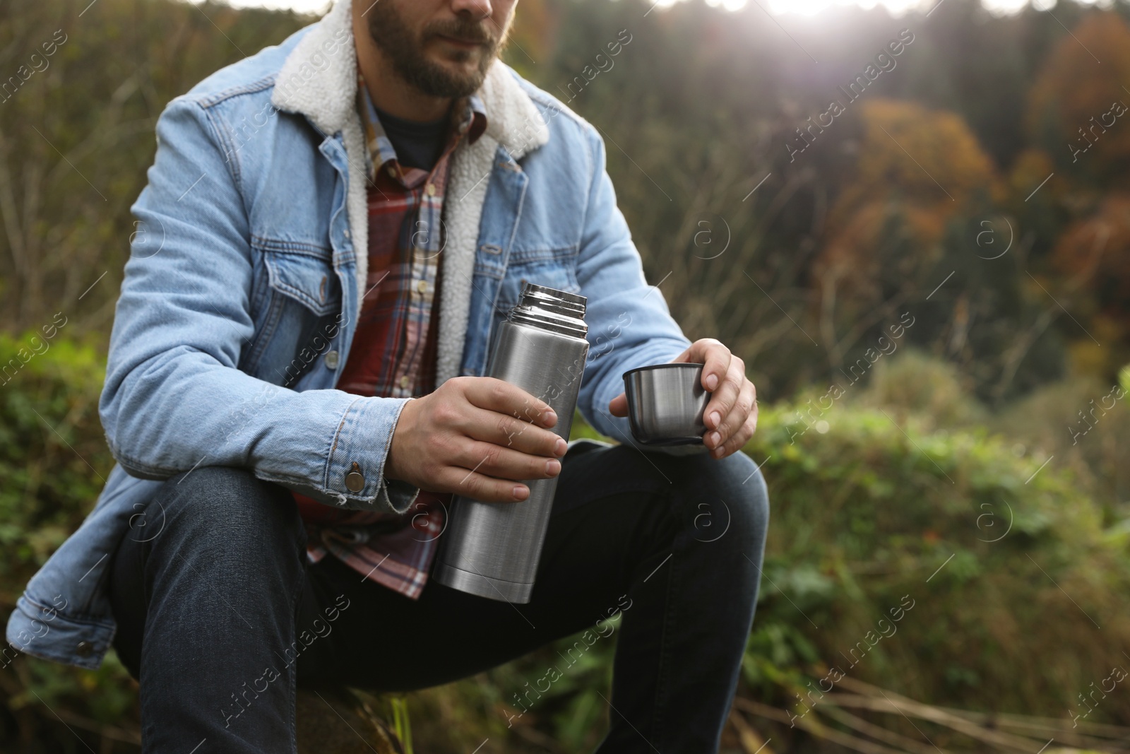 Photo of Man with metallic thermos and cup lid in nature, closeup. Space for text