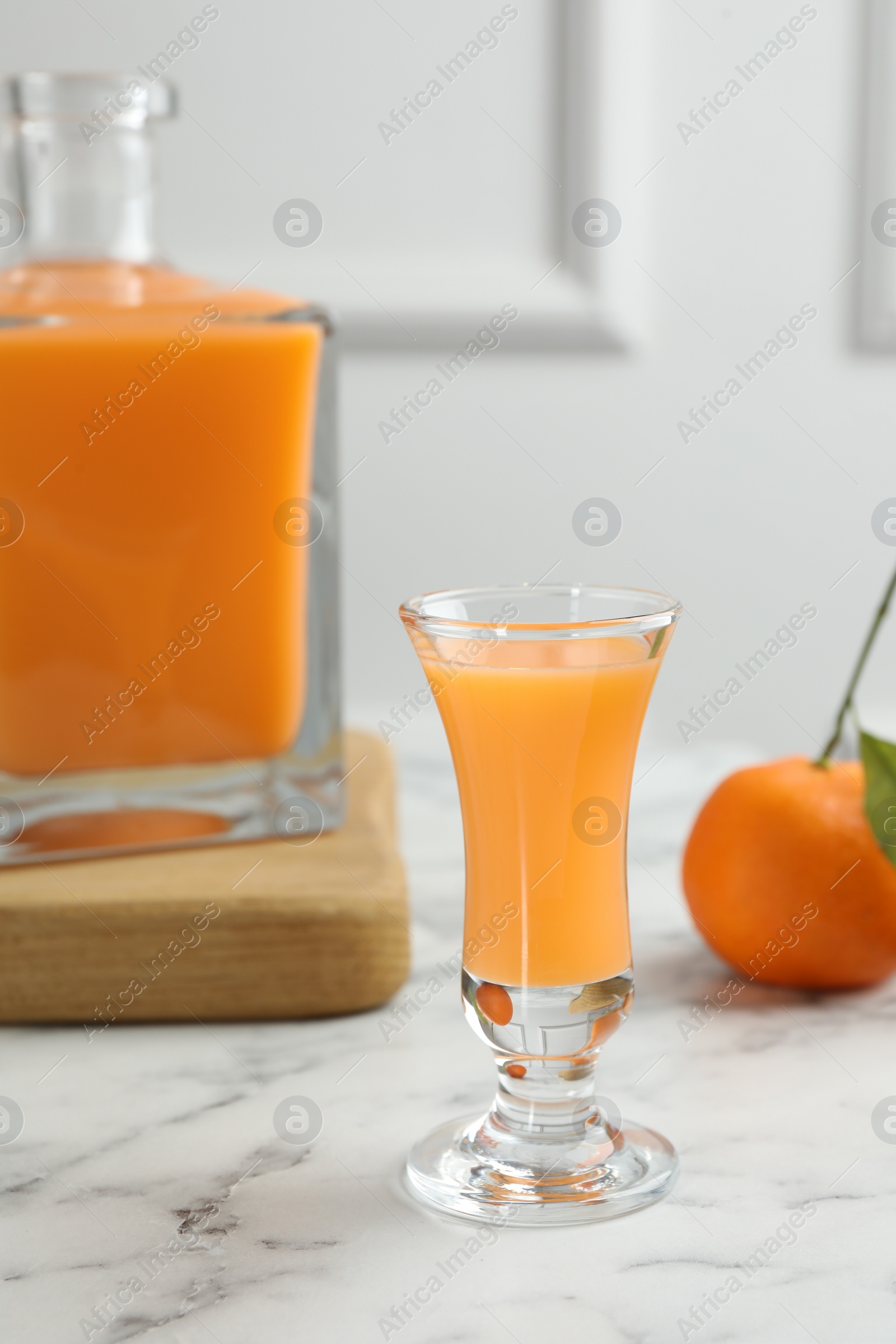 Photo of Delicious tangerine liqueur and fresh fruit on white marble table