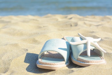 Photo of Stylish slippers and dry starfish on sandy beach near sea, closeup. Space for text