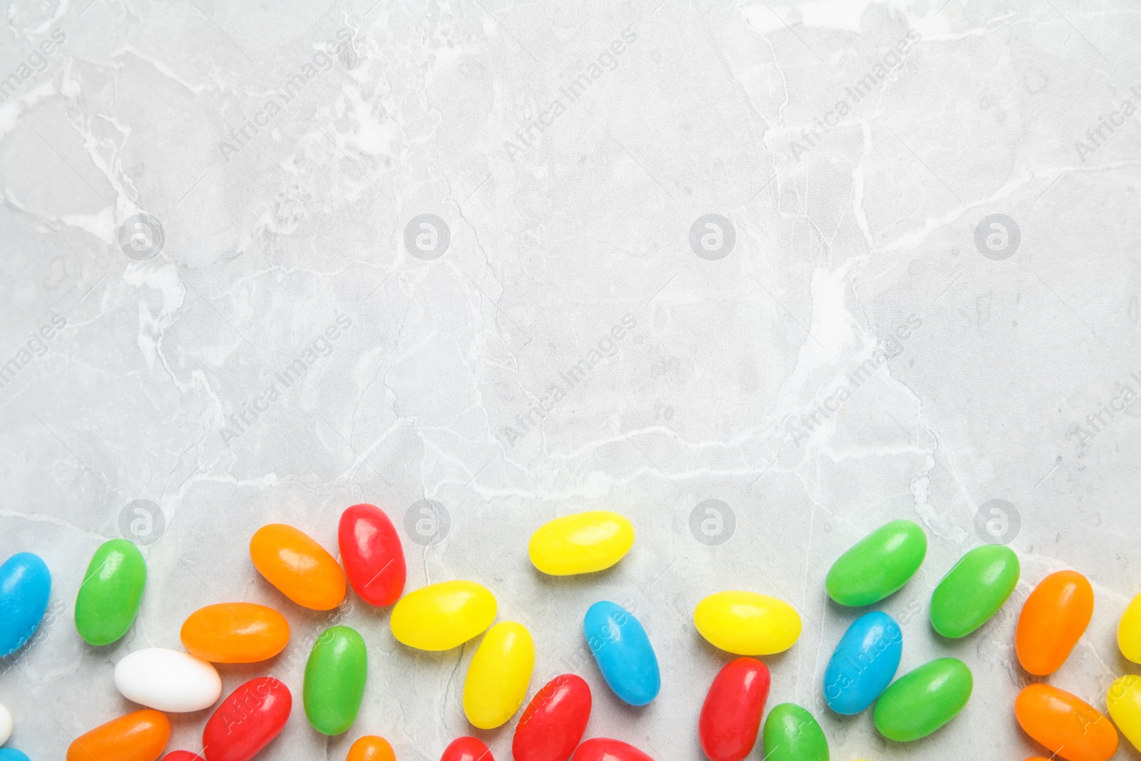 Photo of Flat lay composition with jelly beans on light background. Space for text