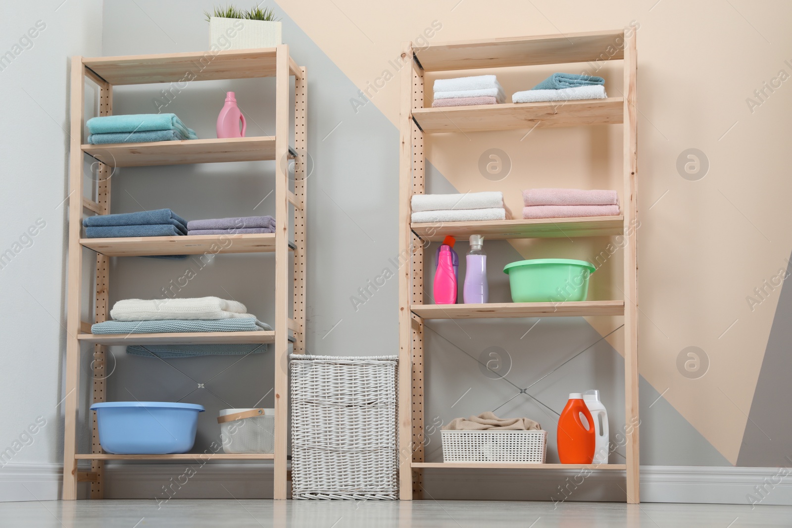 Photo of Wooden shelving units with clean towels and detergents in stylish room interior