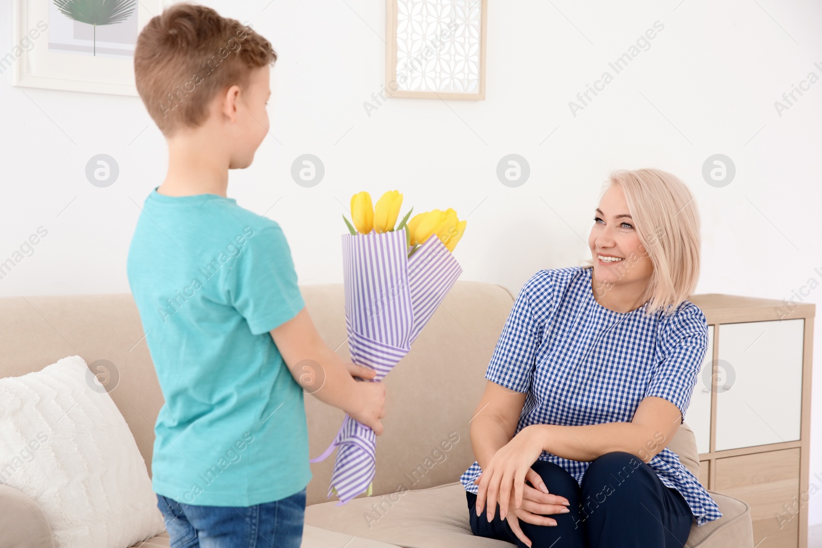 Photo of Little boy congratulating grandmother at home