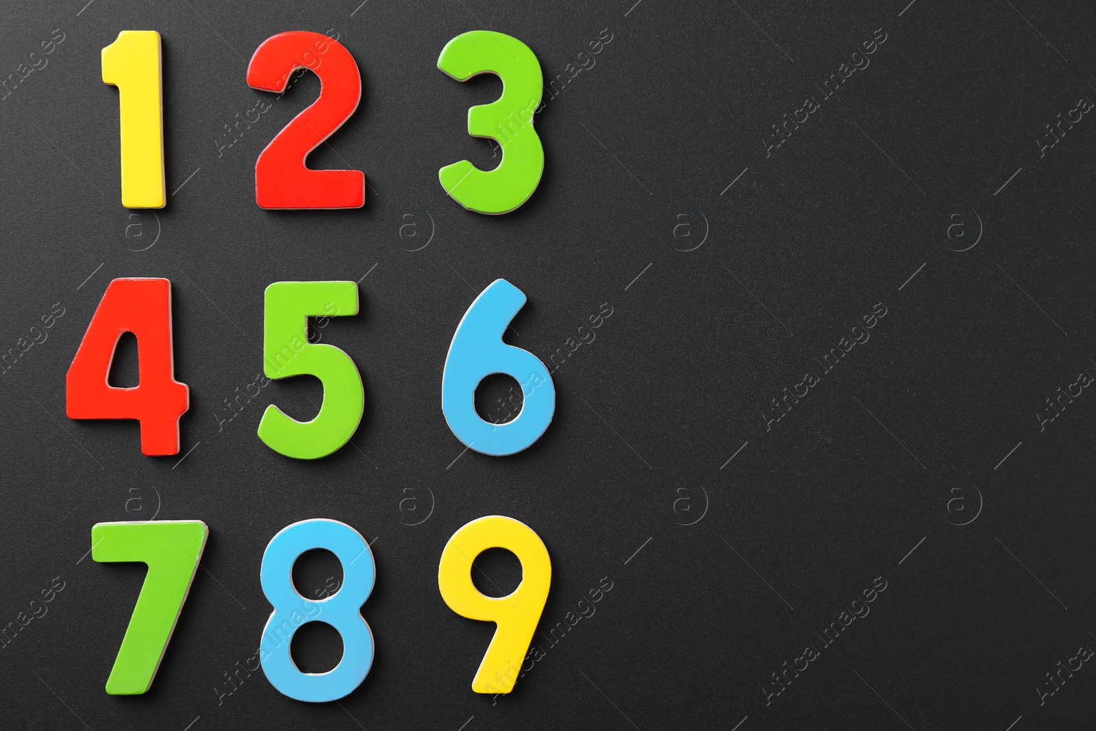 Photo of Colorful numbers on black background, flat lay. Space for text