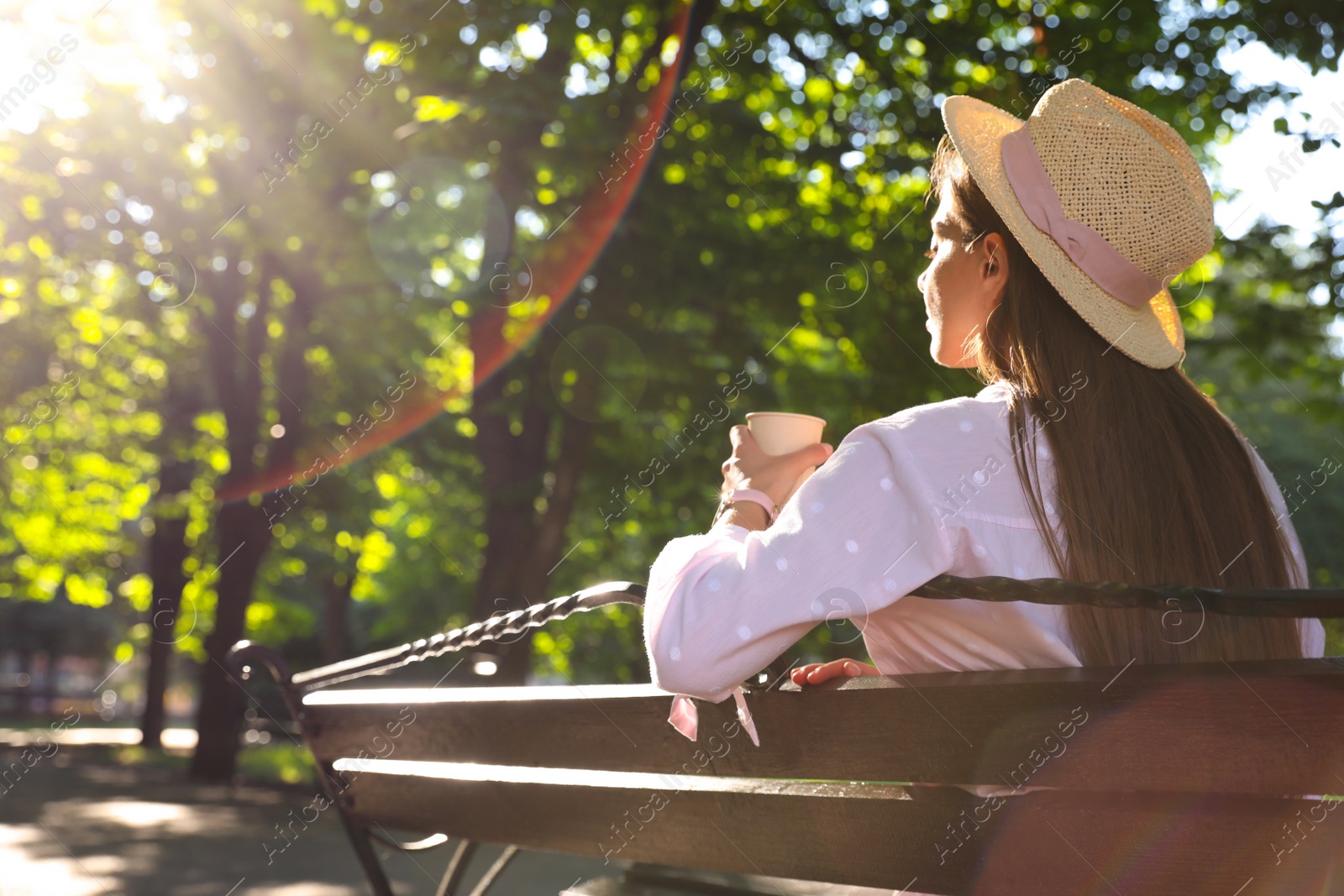 Photo of Woman with drink in park on sunny day, back view. Space for text