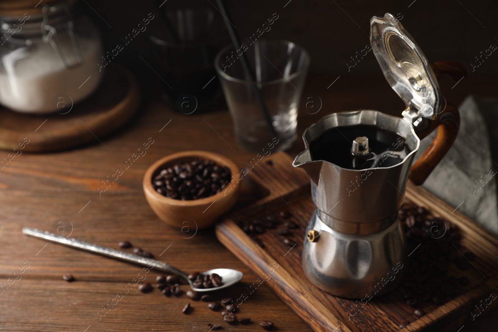 Photo of Brewed coffee in moka pot and beans on wooden table