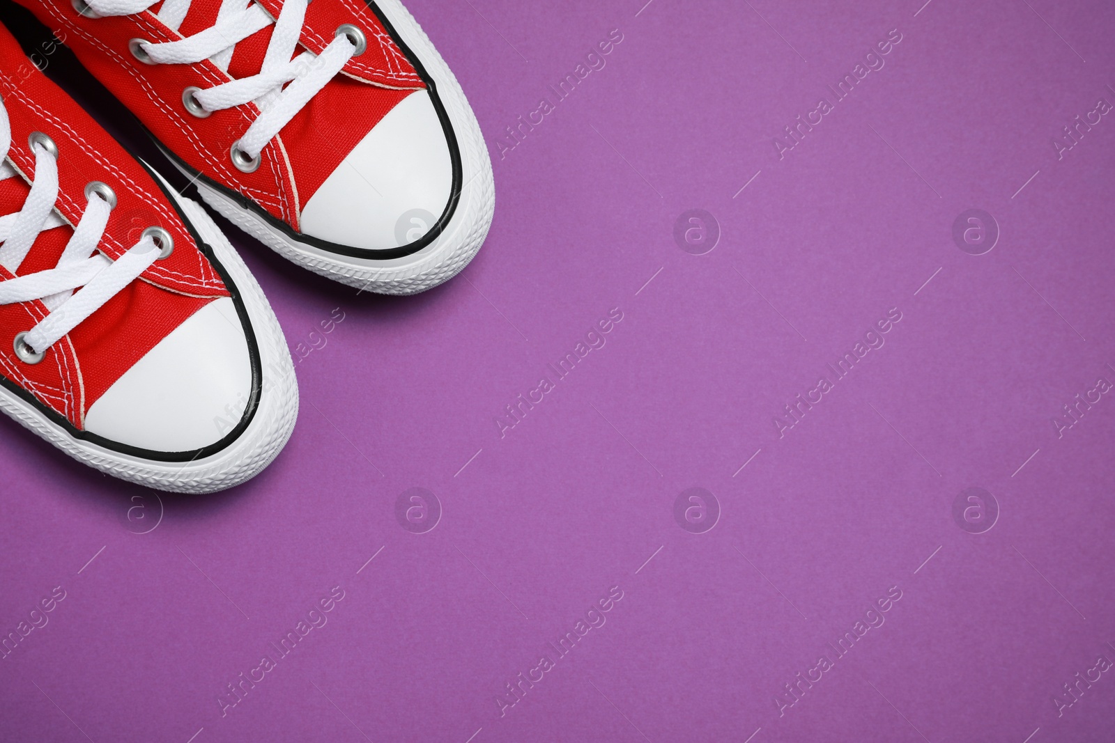 Photo of Pair of new stylish red sneakers on purple background, flat lay. Space for text