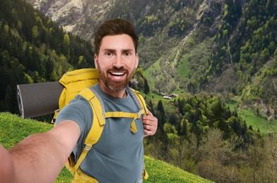 Image of Happy tourist with backpack taking selfie in mountains