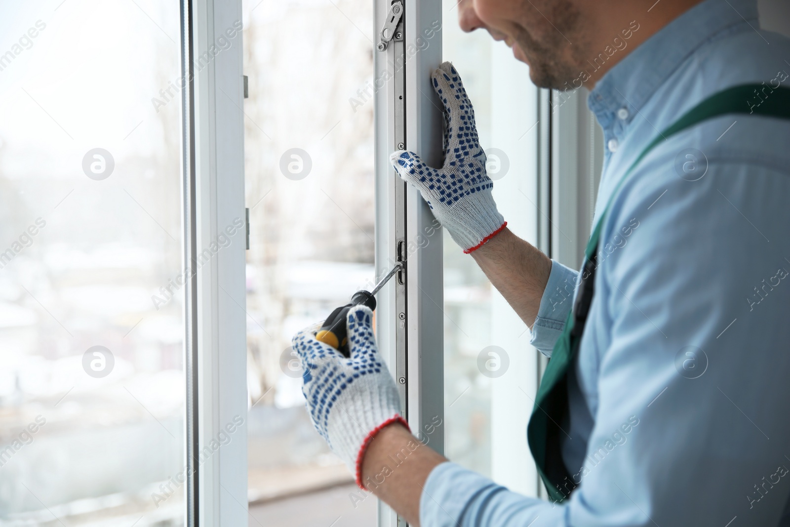 Photo of Construction worker adjusting installed window with screwdriver indoors, closeup