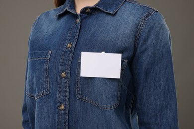 Woman with blank badge on grey background, closeup